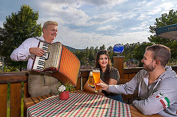 Ein Musiker spielt Akkordeon und sorgt für gute Stimmung bei Gästen im JOSKA Biergarten.